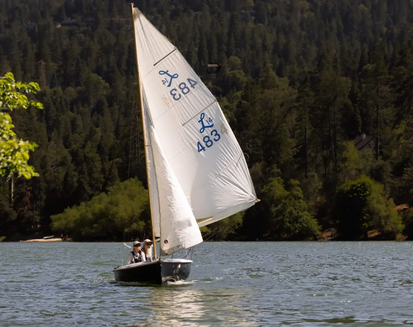 Members sailing a Lido 14 dinghy upwind on Lake Gregory